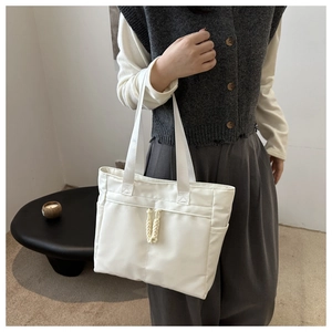 Detailed side view of white minimalist tote bag with drawstring detail and side pockets