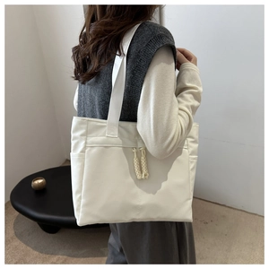Detail of a large white nylon tote bag showing the textured straps and knot zipper pulls