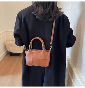 Close-up of caramel woven leather bucket bag with circular handle and thin crossbody strap