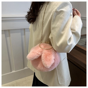 Détail du sac lapin en peluche rose avec poignée en métal doré et chaîne sur un mannequin