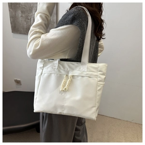 Detail of a large white minimalist tote bag with woven rope accents worn by a model