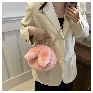 Gros plan du sac en peluche rose avec oreilles de lapin, poignée anneau doré et chaîne
