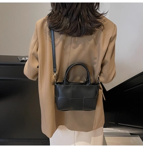 Detail of woven black bucket bag with adjustable gold-tone metal strap hooks