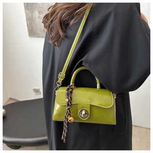 Detail view of avocado green crossbody bag with turn-lock closure and decorative pendant