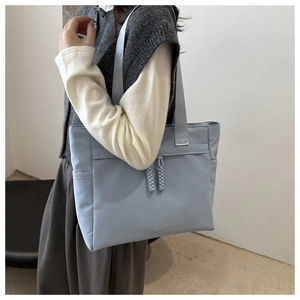 Détail du cabas en nylon bleu clair avec doubles fermetures éclair et poches sur le modèle