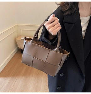Detail view of dark brown woven tote bag featuring wide square weave and metal zipper