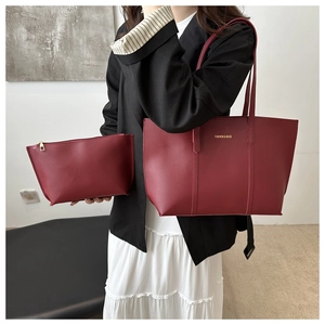 Detailed view of the burgundy faux leather tote bag set with golden hardware and text