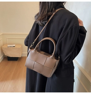 Detailed texture of brown woven bucket bag with top handle and crossbody strap