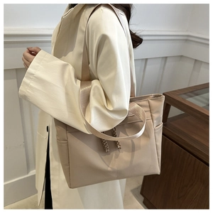 Detail of a large capacity beige tote bag with side pockets and decorative drawstrings