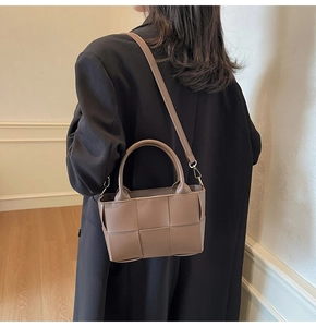 Detail of dark brown woven leather texture with gold hardware on a bucket bag