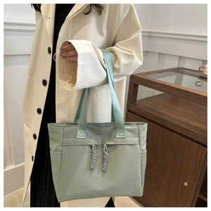 Detail of mint green canvas tote bag featuring decorative woven drawstring and side pocket