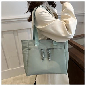 Vista dettagliata di una borsa tote in nylon verde chiaro indossata da una modella