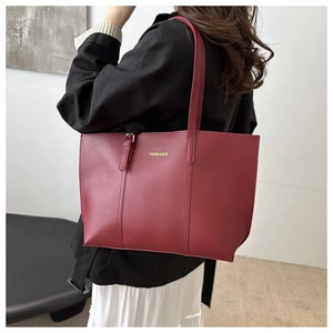 Detail of burgundy matte leather tote bag with elegant stitching and text on a model