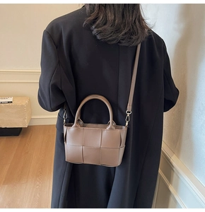 Detail showing the large woven texture and dual handles of this brown leather bucket bag