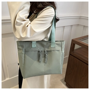 Detail of mint green nylon tote bag featuring durable shoulder straps and rope accents