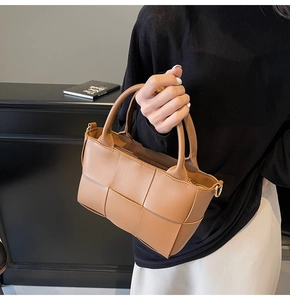 Detail of a brown woven bucket bag featuring premium leather craftsmanship and gold metal D-rings