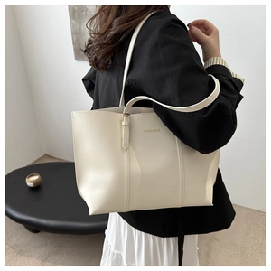 Side view of beige leather tote bag with Fashion & Bags text on a shoulder-carried model