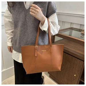 Detailed view of caramel brown tote bag featuring gold FASHION & BAGS lettering