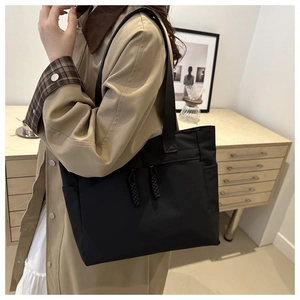 Minimalist black canvas tote bag shown at a 45-degree angle on a female model