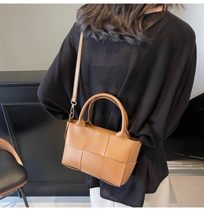 Detail of woven brown leather handbag showing large grid pattern and top handle texture