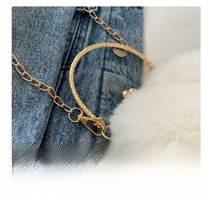 Détail du crochet en métal doré et anneau gravé sur denim et peluche blanche