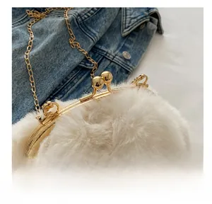 Détail du fermoir à boule dorée sur un sac en peluche blanc cassé avec chaîne en métal