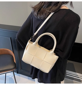 Detail view of cream woven tote bag showing luxury square weave texture and gold hardware