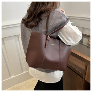 Détail d'un sac cabas en cuir mat marron foncé avec inscription FASHION & BAGS porté à l'épaule