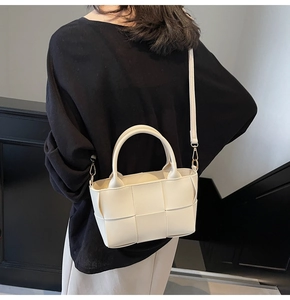 Detailed view of a white woven bucket bag showing its premium texture and crossbody style