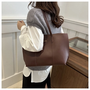 Detail of coffee brown leather tote bag with thin straps and gold embossed lettering