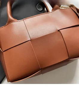 Close-up of woven caramel leather texture and Intrecciato craft on the bucket handbag