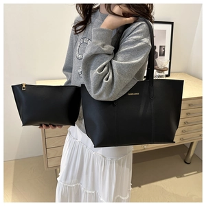Detail of black faux leather tote bag with small pouch showing texture and gold lettering