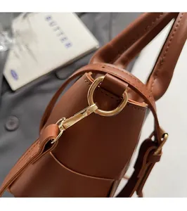 Close-up of premium golden hardware and circular buckle on a brown leather handbag