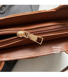 Macro detail of smooth golden zipper and lychee pattern leather on brown bucket bag