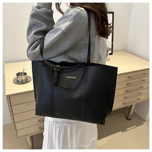 Detail view of large black leather tote bag with gold lettering and long shoulder straps