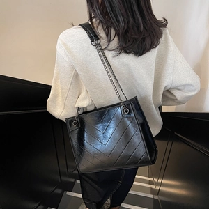 Quilted black chain tote bag with chevron stitching shown on model in modern setting