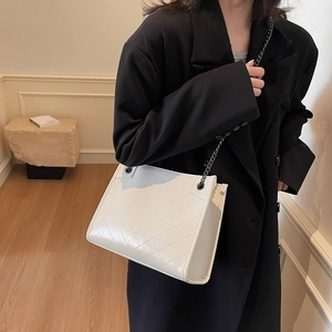 White quilted faux leather tote bag with V-shaped stitching and dark metal chain strap