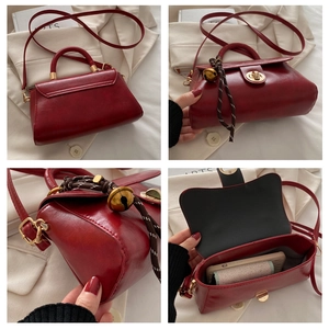 Detail view of burgundy tote bag showing twist lock, bell charm and leather texture