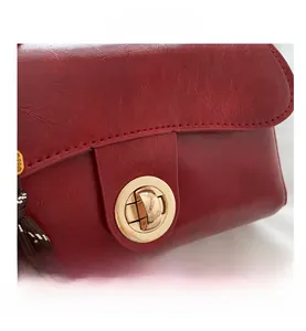 Close-up of burgundy leather handbag featuring a golden rotary lock and pebble texture