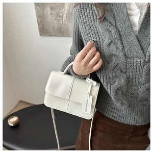 Detail of white rectangle crossbody bag with mixed texture stitching and fashion tag