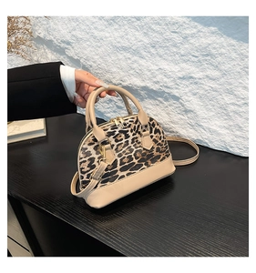 Detail of leopard print shell bag with top handles and adjustable shoulder strap