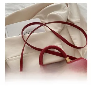Detail of red glossy leather bag with woven flap and adjustable golden hardware