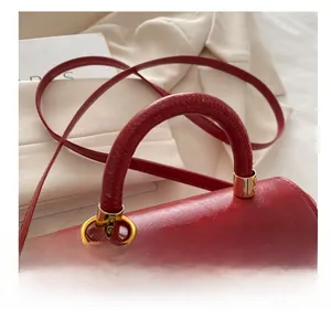 Close-up of deep red vintage handbag with round handle and gold ring buckle detail