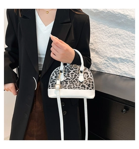 Detail view of stylish leopard print shell bag with white leather contrast and gold zipper