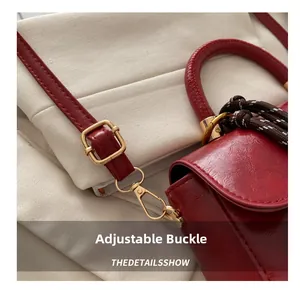 Detailed close-up of the golden adjustable buckle on a red textured leather handbag