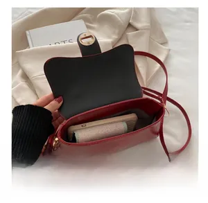 Macro view of red glossy crossbody bag interior showing spacious storage and golden clasp