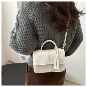 Détail du sac à main bicolore en similicuir avec poignée élégante et pendentif mode