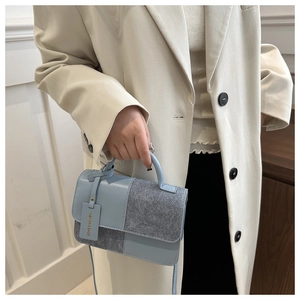 Detail of the blue and grey patchwork handbag showing textured materials and handle