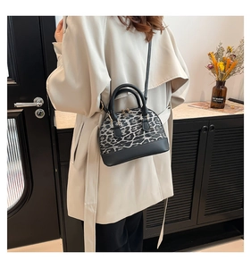 Chic leopard print shell bag shown as a crossbody on a model for a stylish casual look