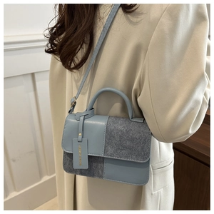 Detail of light blue crossbody square bag with mixed textures and hanging fashion tag